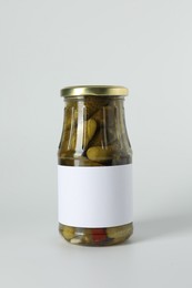 Pickled cucumbers in jar on light background