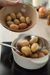 Woman taking potatoes from pot on stove, closeup