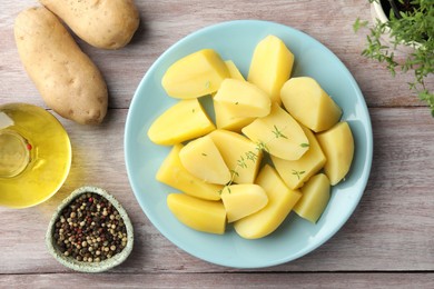 Photo of Tasty potatoes, microgreens, peppercorns and oil on wooden table, top view