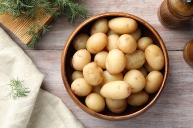 Photo of Boiled potatoes in bowl and dill on wooden table, top view