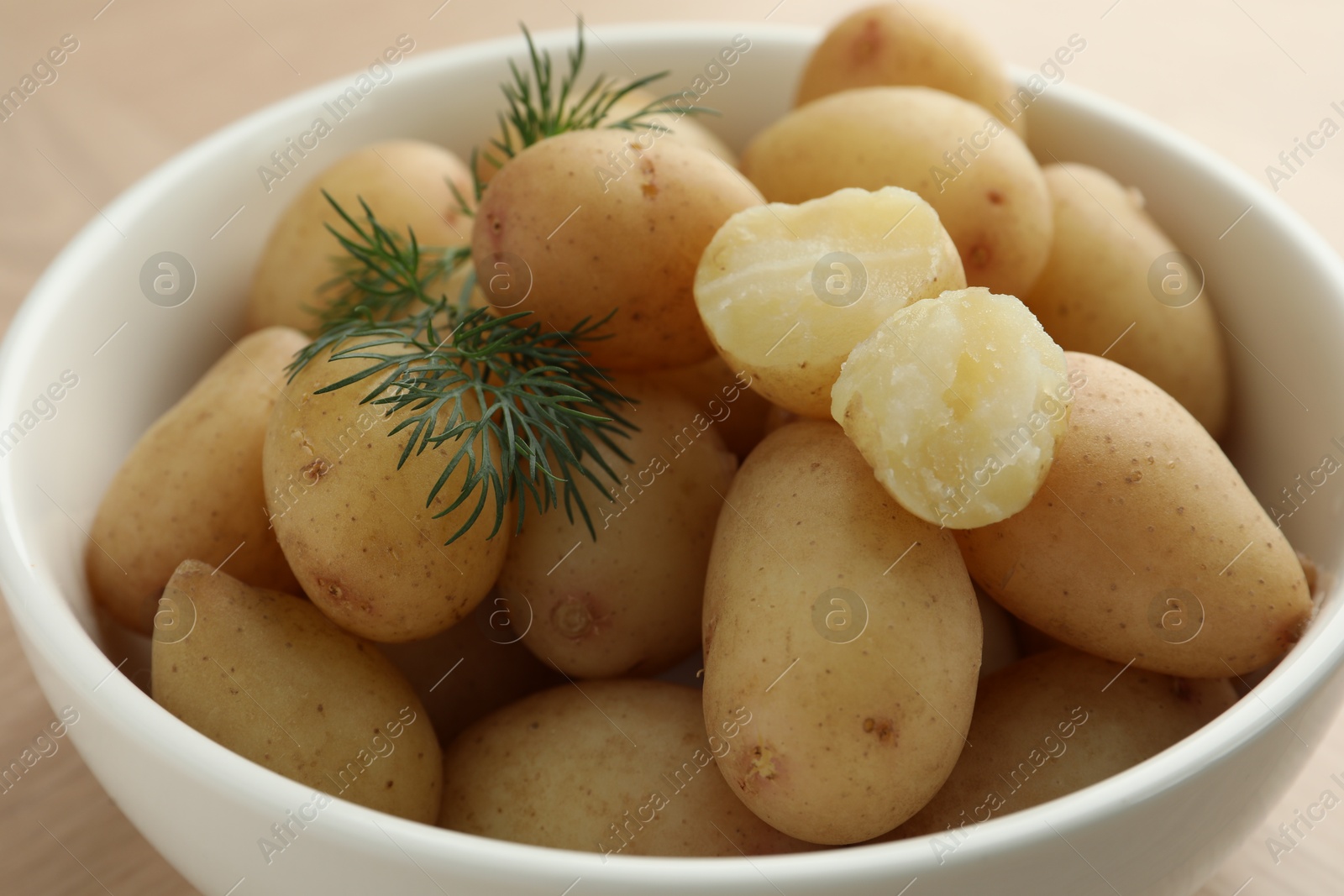 Photo of Boiled potatoes with dill in bowl on table, closeup