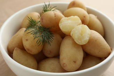 Photo of Boiled potatoes with dill in bowl on table, closeup