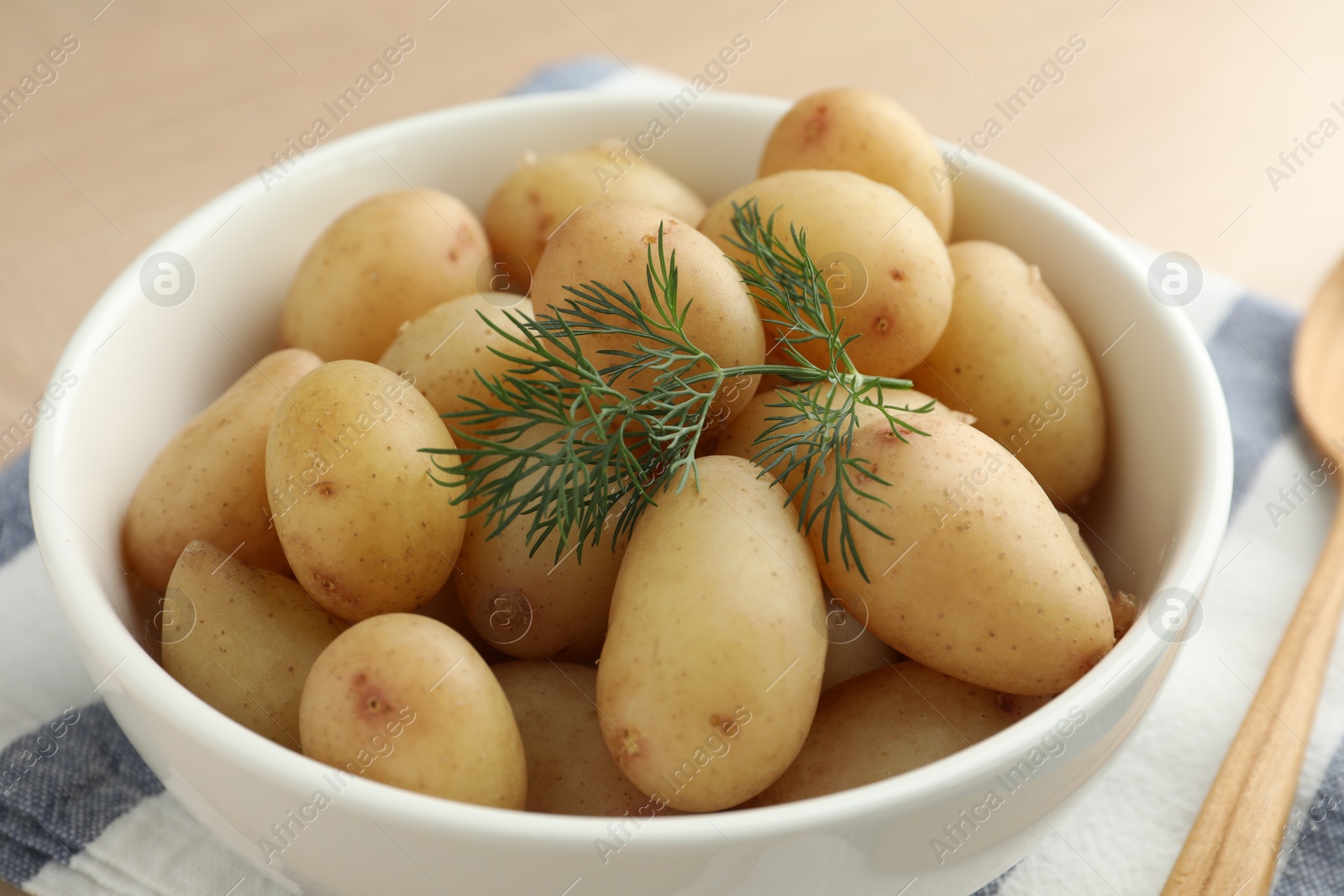 Photo of Boiled potatoes with dill in bowl on table