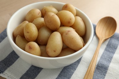 Boiled potatoes in bowl and wooden spoon on table