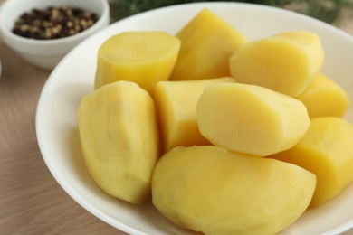 Photo of Boiled potatoes in bowl on wooden table, closeup