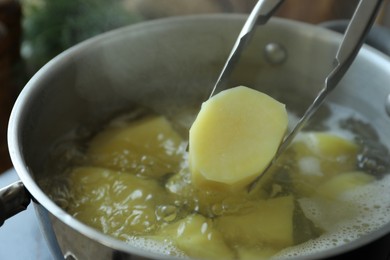 Taking boiled potato from pot on stove, closeup