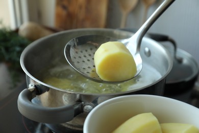 Taking boiled potato from pot on stove, closeup