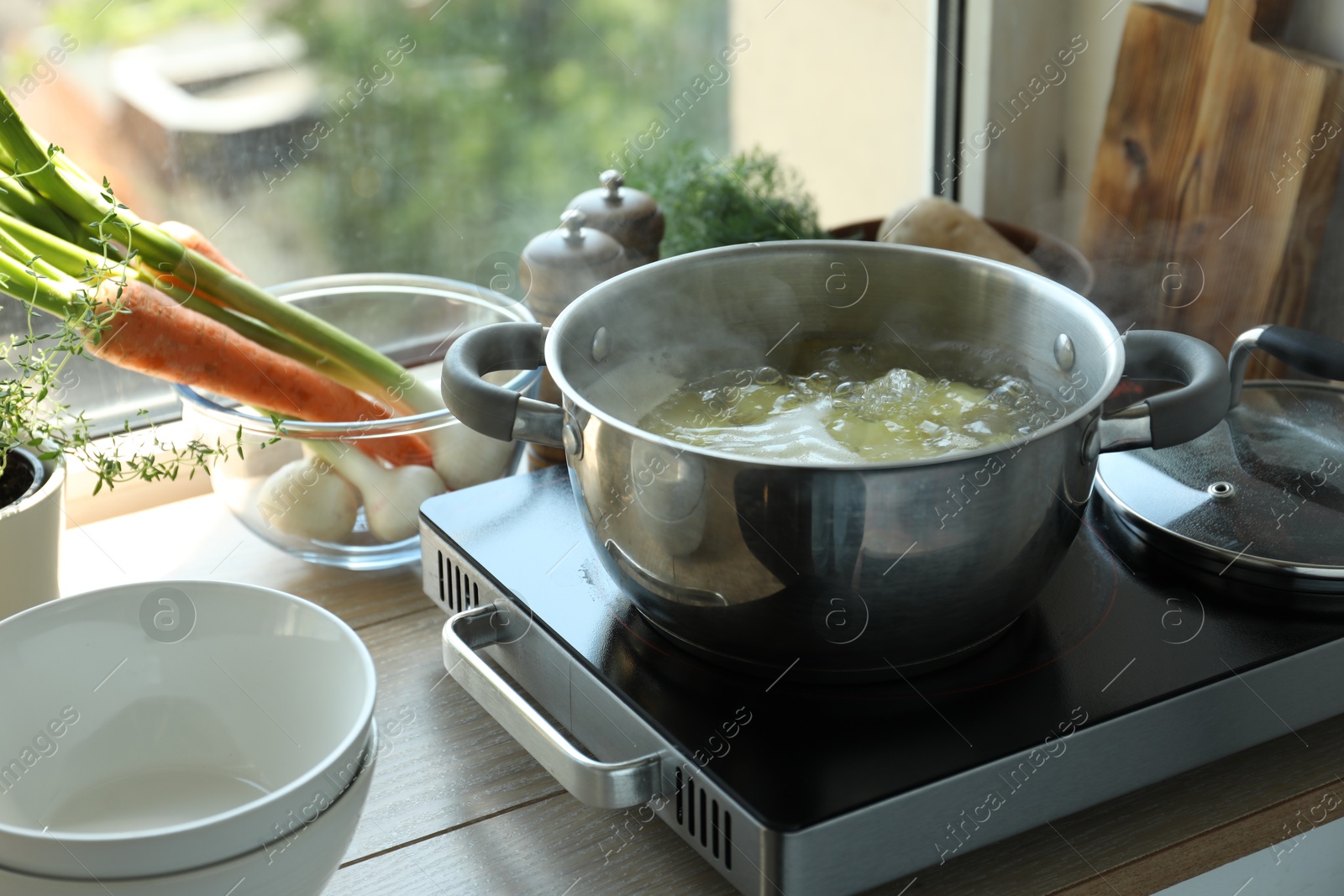 Photo of Boiling potatoes in pot on stove in kitchen