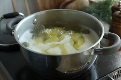 Photo of Boiling potatoes in pot on stove in kitchen