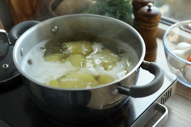 Photo of Boiling potatoes in pot on stove in kitchen