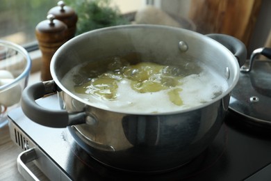 Photo of Boiling potatoes in pot on stove in kitchen