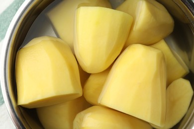 Photo of Raw potatoes in pot with water, top view