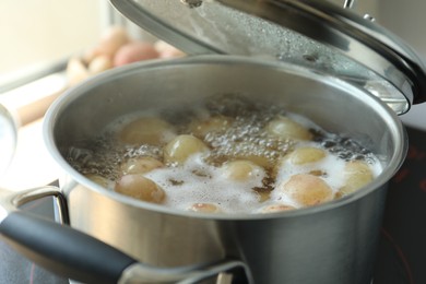 Boiling potatoes in pot on stove in kitchen, closeup