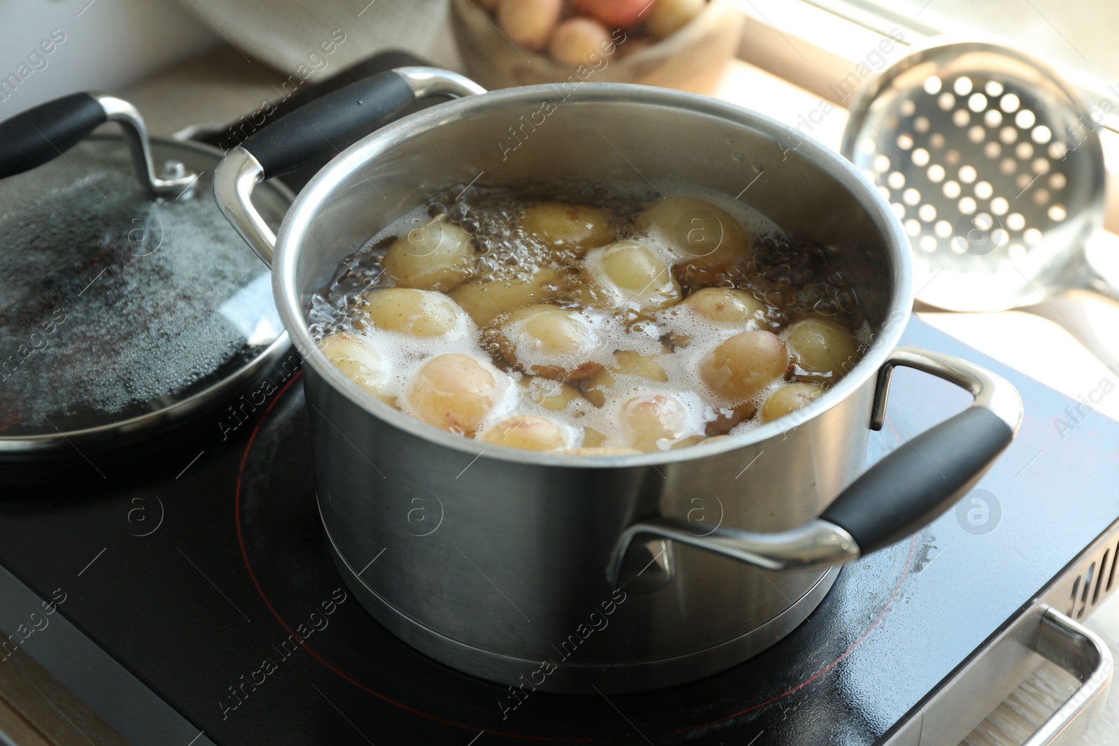 Photo of Boiling potatoes in pot on stove in kitchen