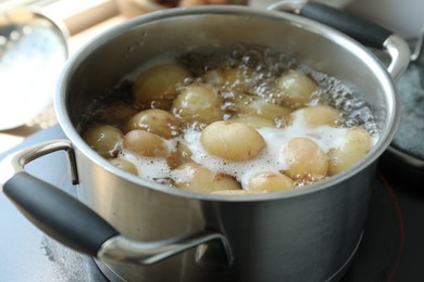 Photo of Boiling potatoes in pot on stove in kitchen