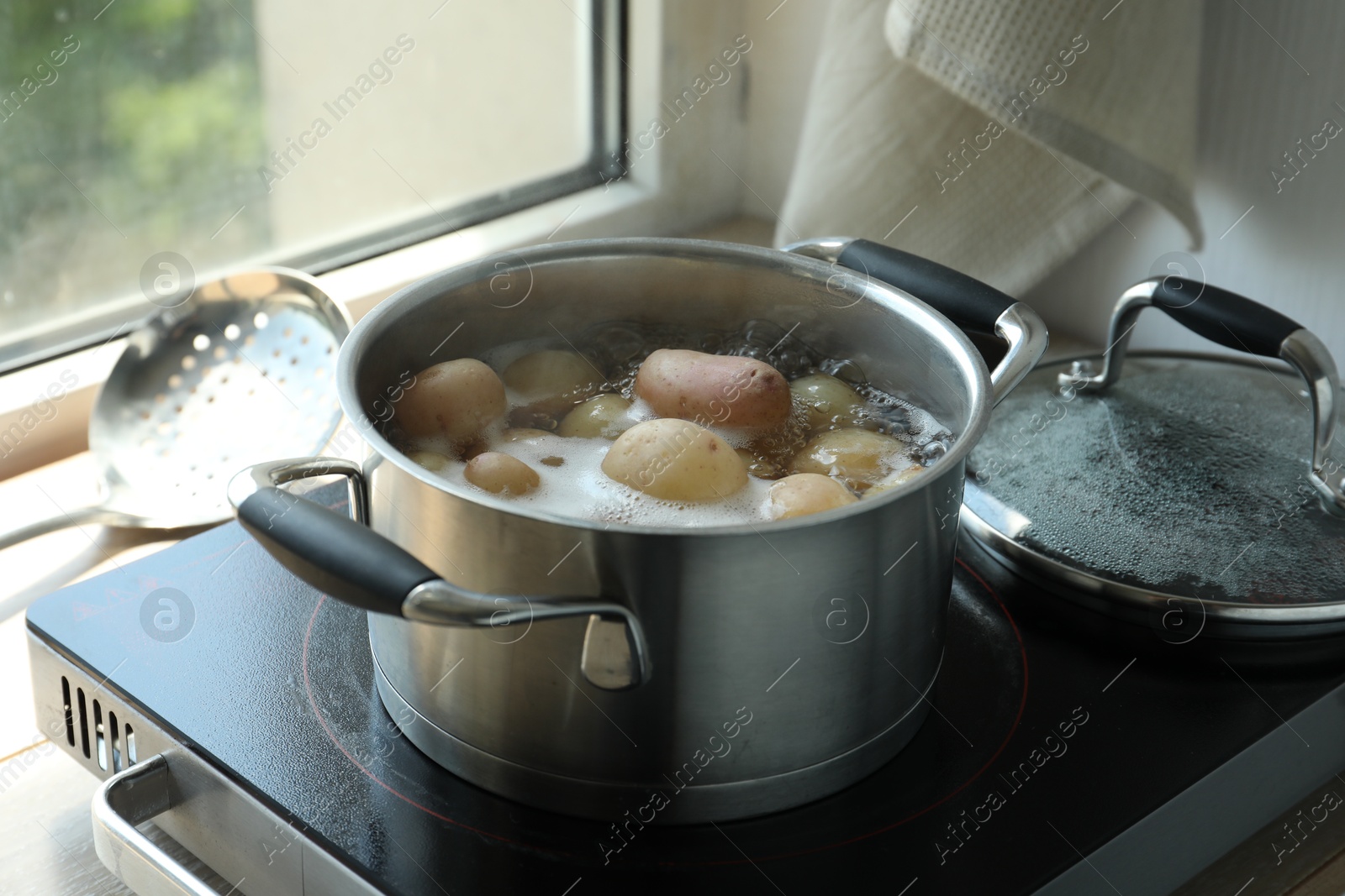 Photo of Boiling potatoes in pot on stove in kitchen