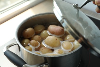 Photo of Boiling potatoes in pot on stove in kitchen, closeup