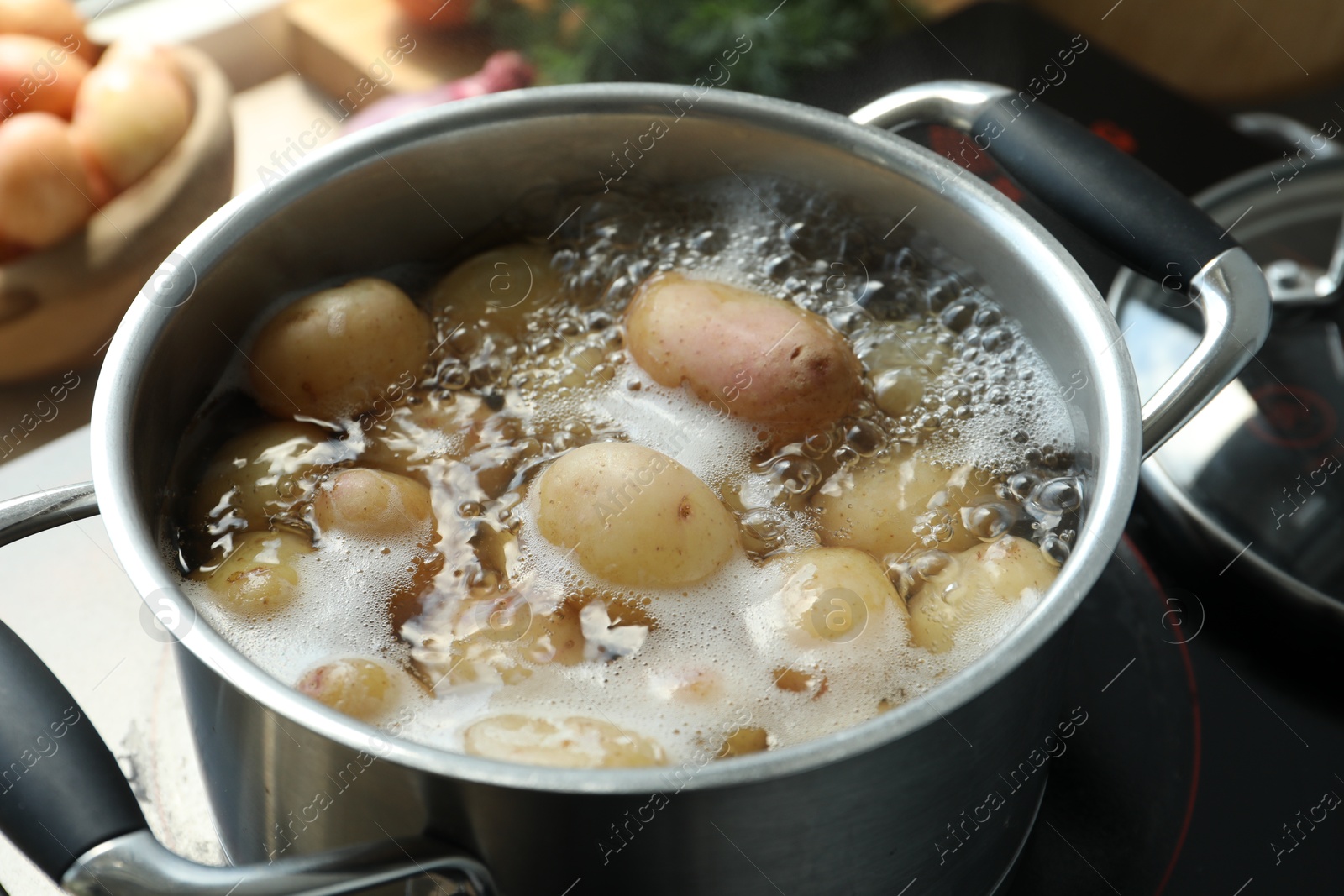 Photo of Boiling potatoes in pot on stove in kitchen, closeup