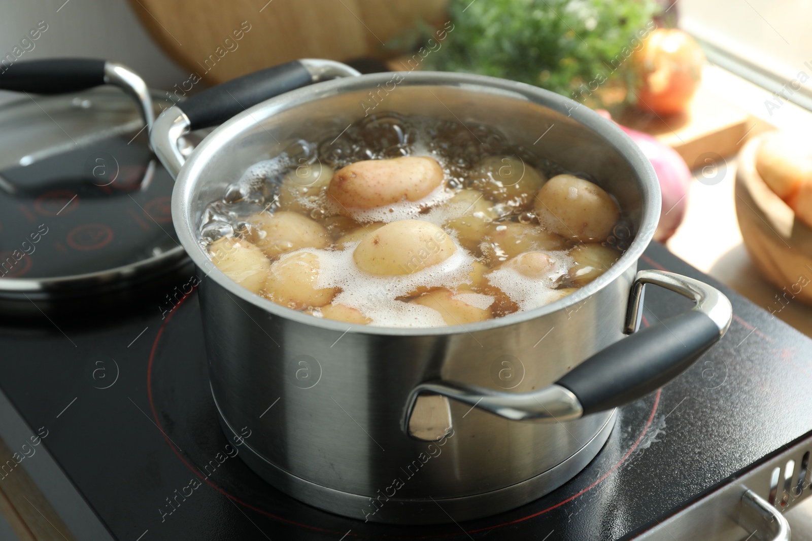 Photo of Boiling potatoes in pot on stove in kitchen