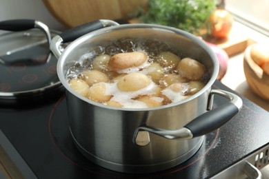 Photo of Boiling potatoes in pot on stove in kitchen