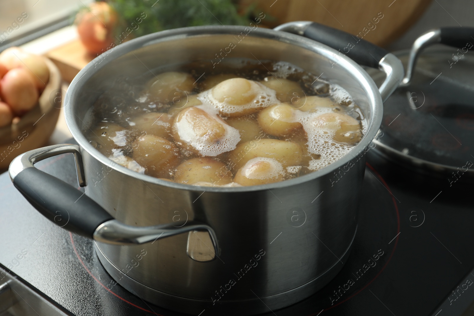 Photo of Boiling potatoes in pot on stove in kitchen