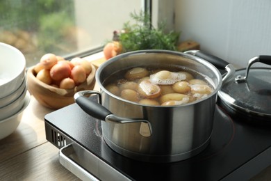 Photo of Boiling potatoes in pot on stove in kitchen