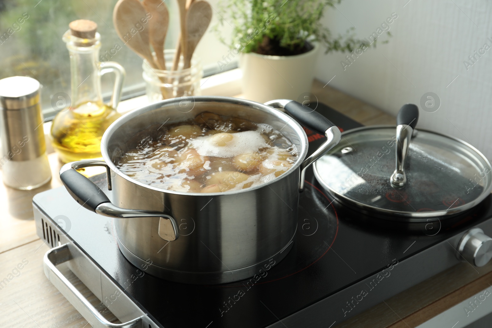 Photo of Boiling potatoes in pot on stove in kitchen