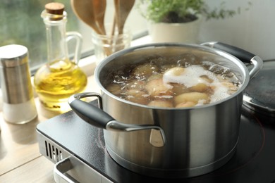 Photo of Boiling potatoes in pot on stove in kitchen