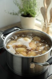 Photo of Boiling potatoes in pot on stove in kitchen