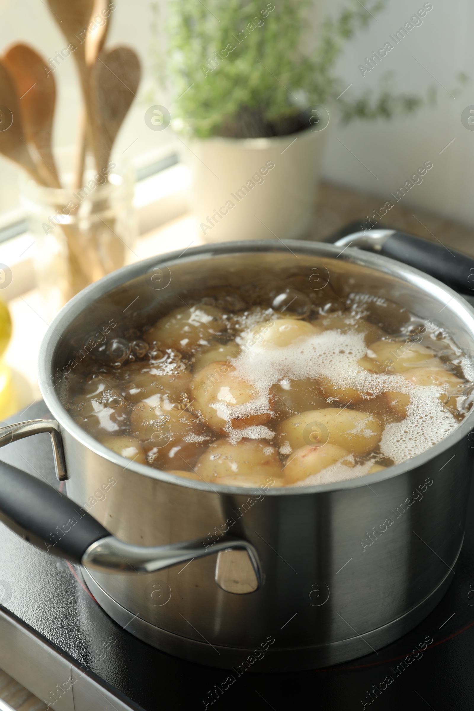 Photo of Boiling potatoes in pot on stove in kitchen