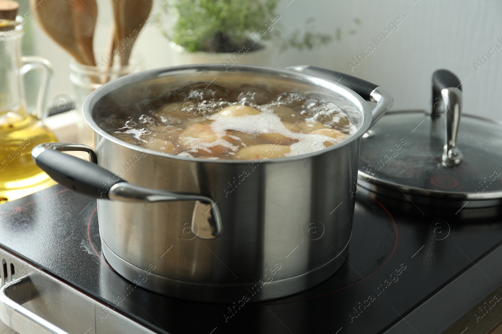 Photo of Boiling potatoes in pot on stove in kitchen