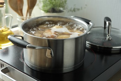 Photo of Boiling potatoes in pot on stove in kitchen