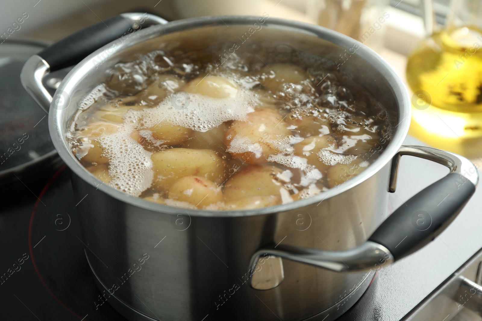 Photo of Boiling potatoes in metal pot on stove, closeup