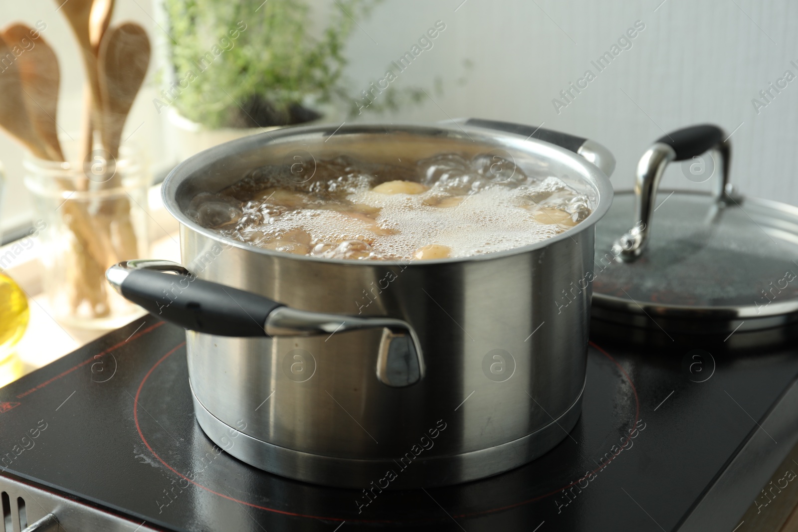 Photo of Boiling potatoes in pot on stove in kitchen