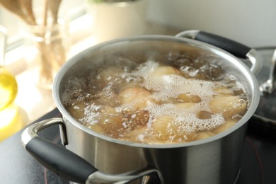 Photo of Boiling potatoes in metal pot on stove, closeup