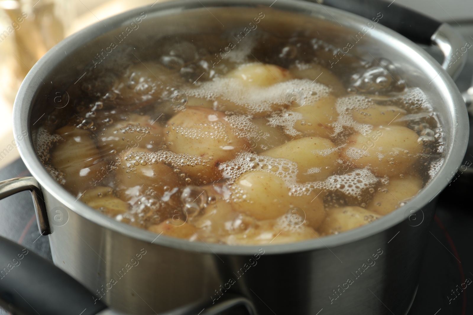 Photo of Boiling potatoes in pot on stove, closeup