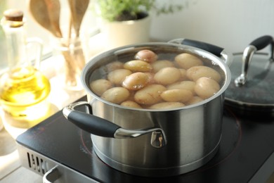 Photo of Boiling potatoes in pot on stove in kitchen