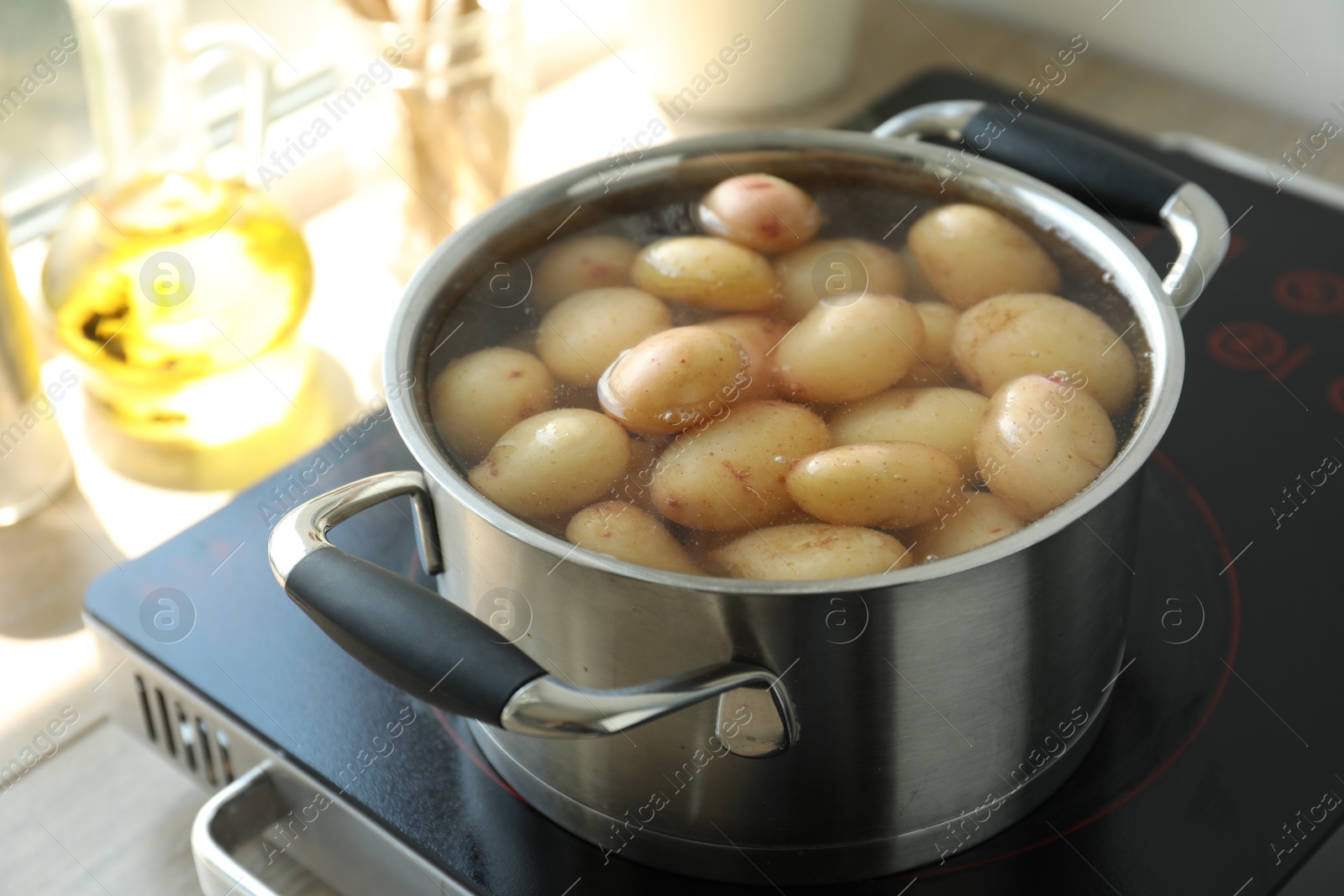 Photo of Boiling potatoes in pot on stove in kitchen