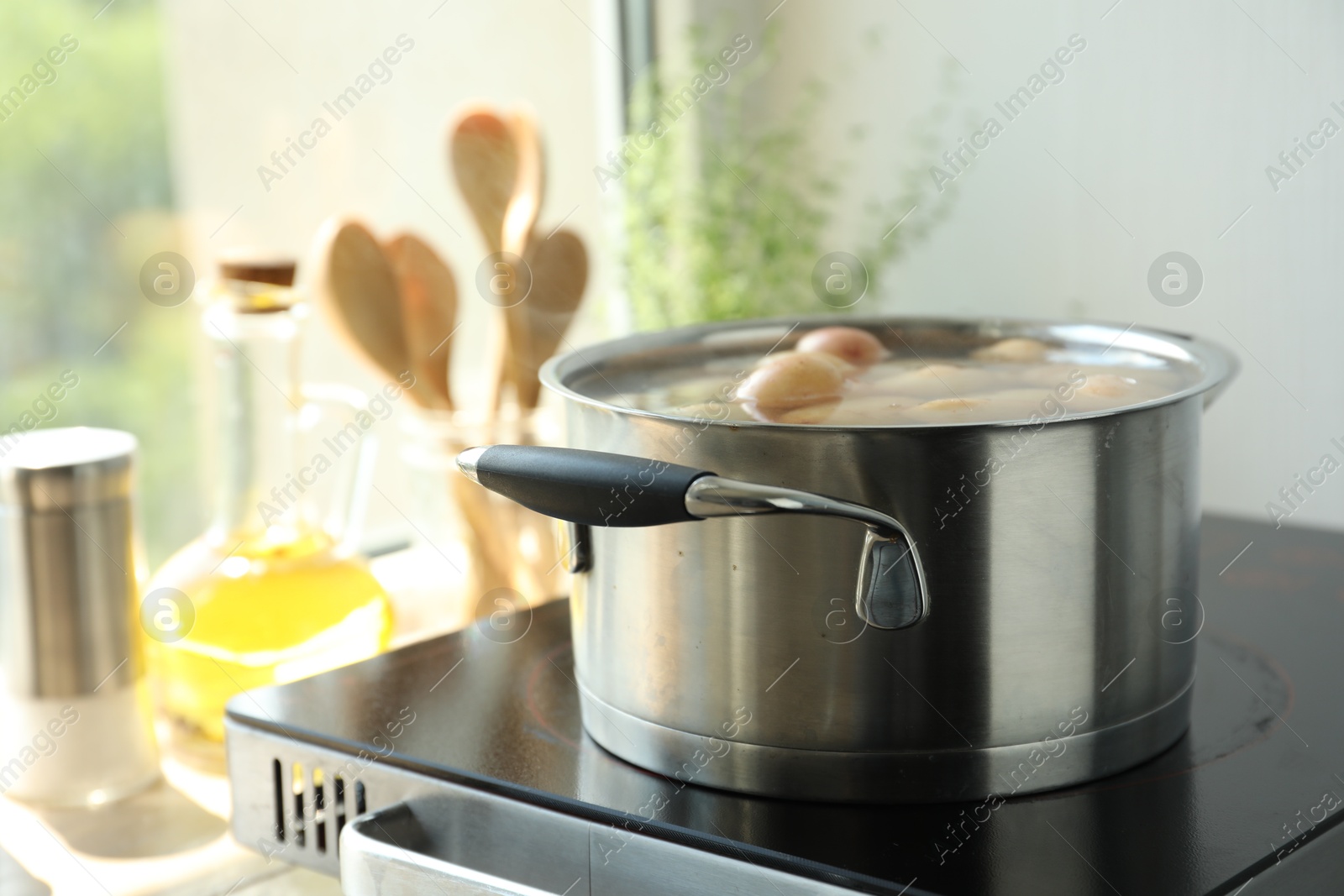 Photo of Boiling potatoes in pot on stove in kitchen