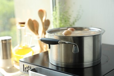 Photo of Boiling potatoes in pot on stove in kitchen