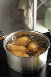 Photo of Boiling potatoes in saucepan on stove in kitchen