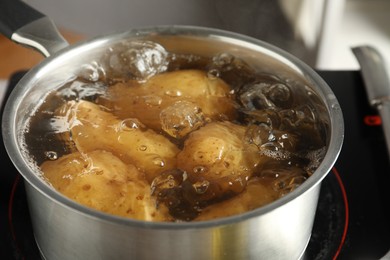 Photo of Boiling potatoes in saucepan on stove, closeup