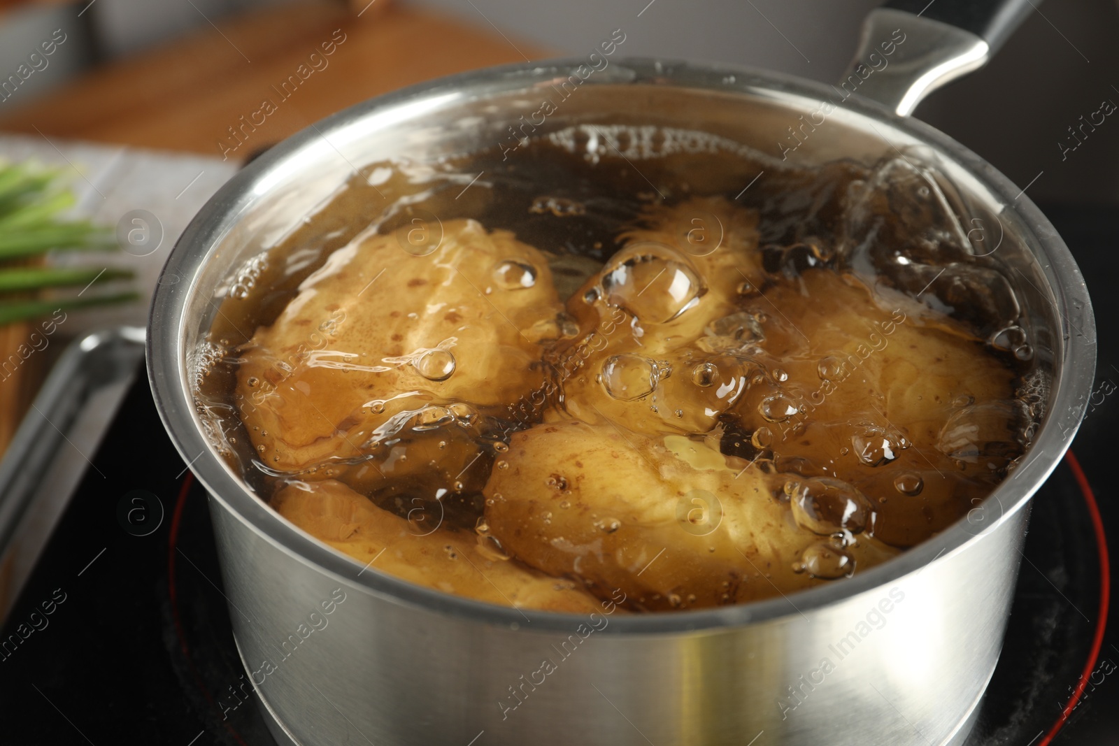 Photo of Boiling potatoes in saucepan on stove, closeup