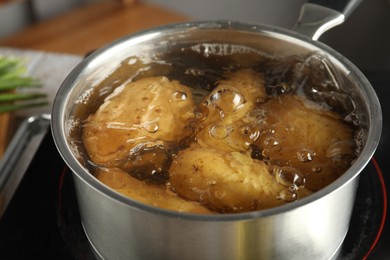 Boiling potatoes in saucepan on stove, closeup