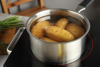 Boiling potatoes in saucepan on stove in kitchen