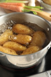 Boiling potatoes in metal pot on stove, closeup