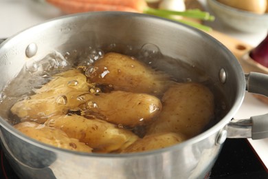 Boiling potatoes in metal pot on stove, closeup