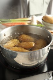 Photo of Boiling potatoes in metal pot on stove