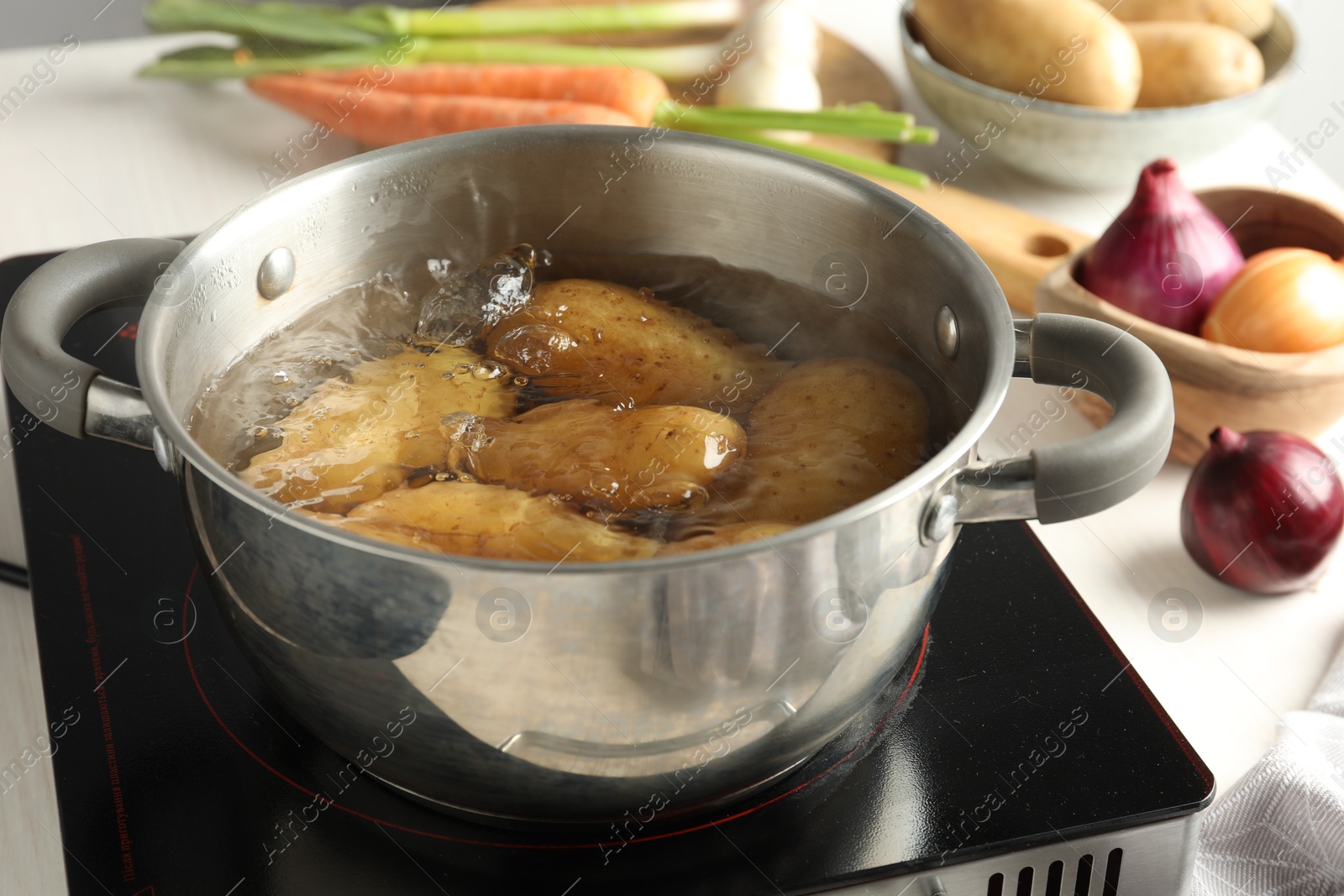 Photo of Boiling potatoes in metal pot on stove