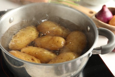 Photo of Boiling potatoes in metal pot on stove, closeup